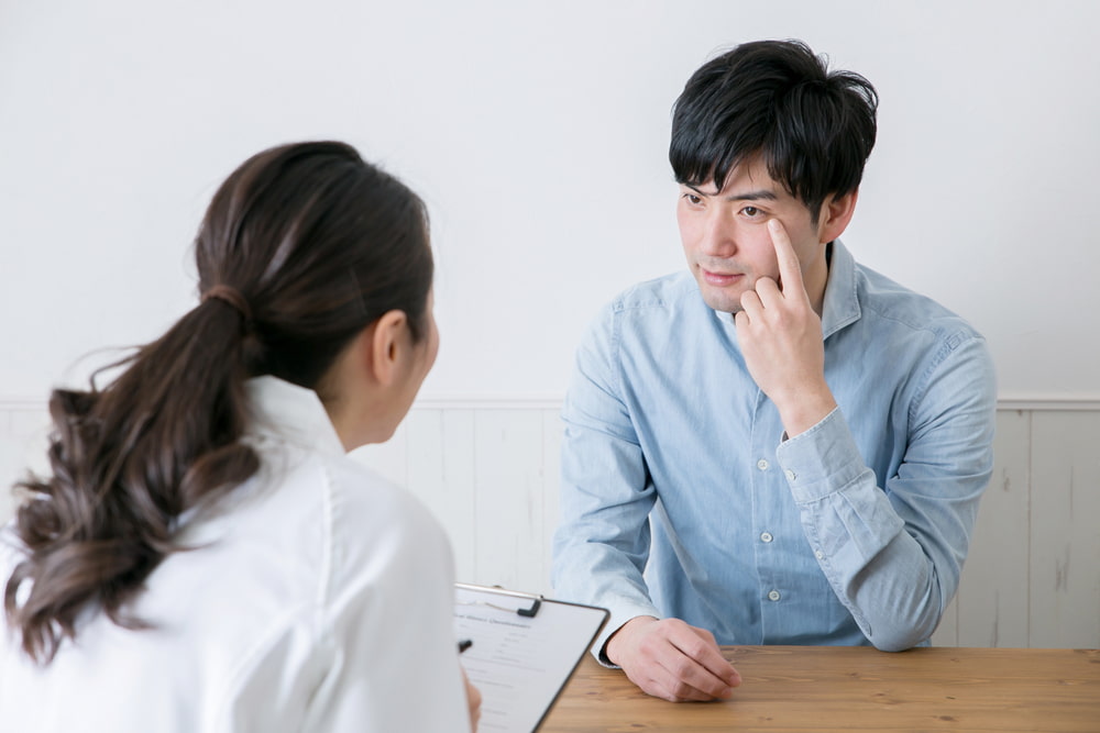man talking to eye doctor about pterygium symptoms