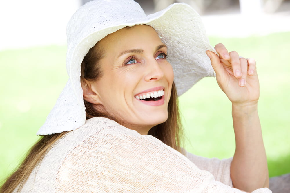 WOman in a hat hanging out outside and smiling